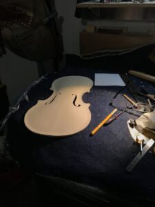 A violin top plate with f holes cut out on a workbench